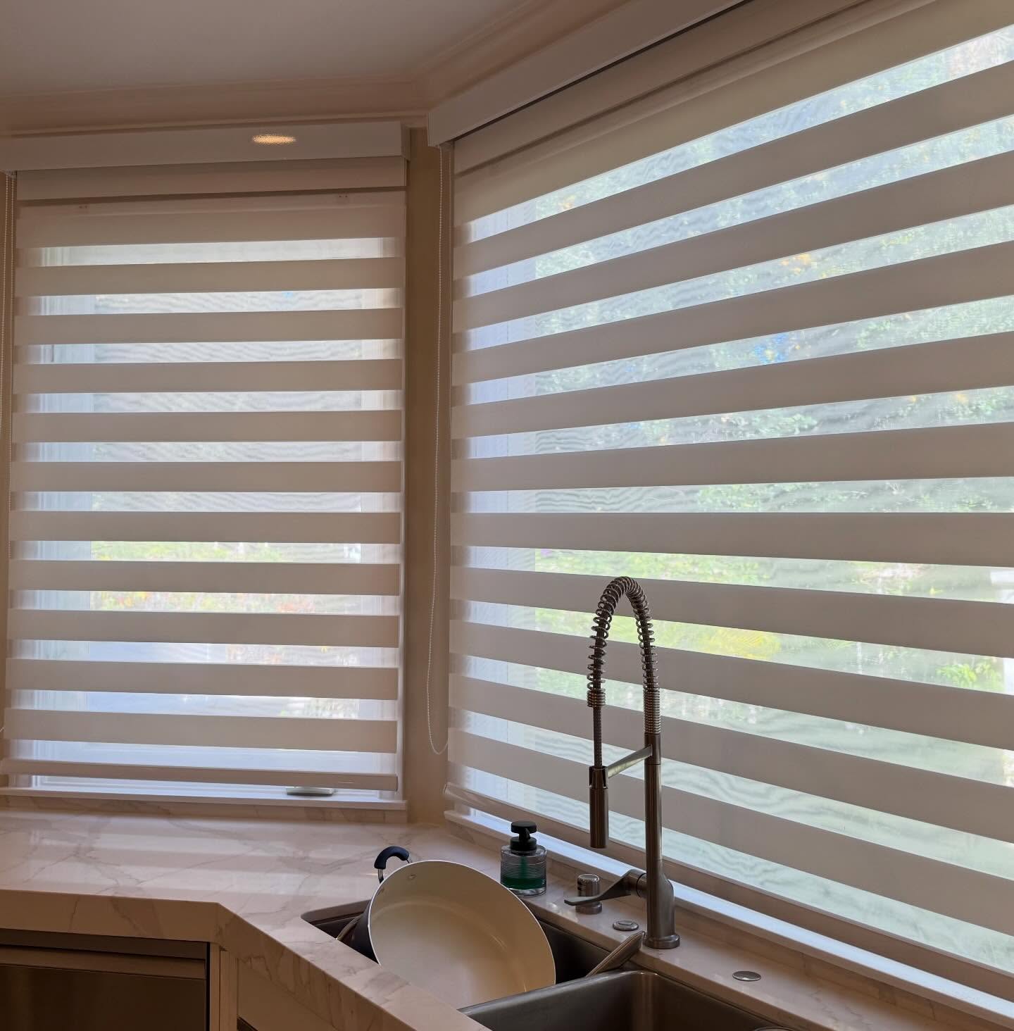 Zebra shades on adjacent windows with the bands offset for a view through
