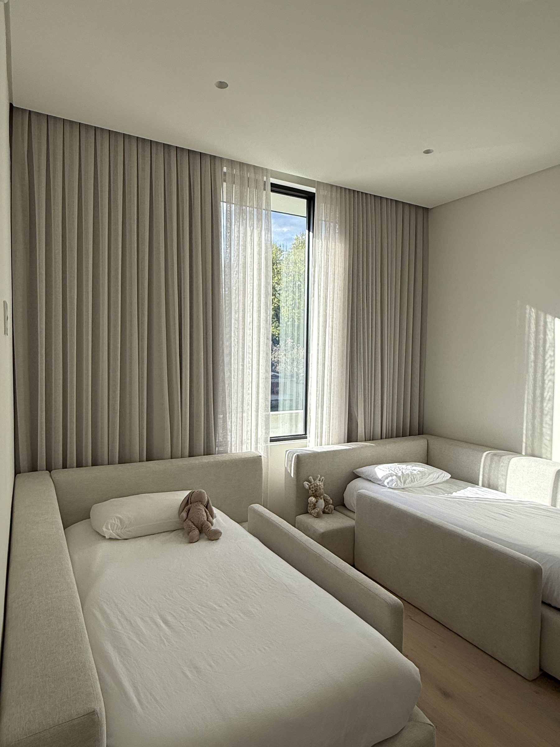 Floor-to-ceiling taupe drapery on a ceiling track in a San Diego bedroom