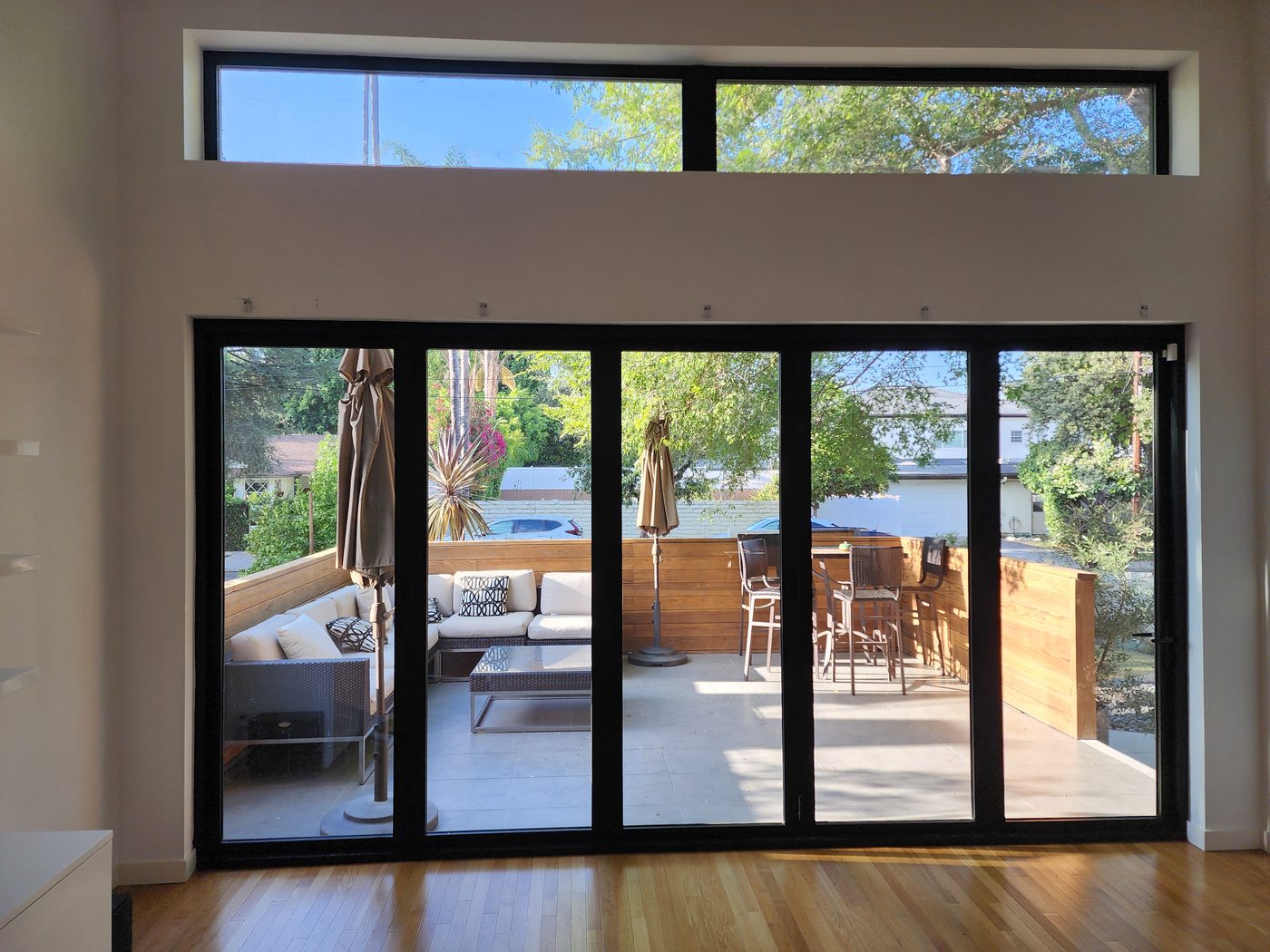 A wide multi-panel slider open to a San Diego deck with motorized shades raised