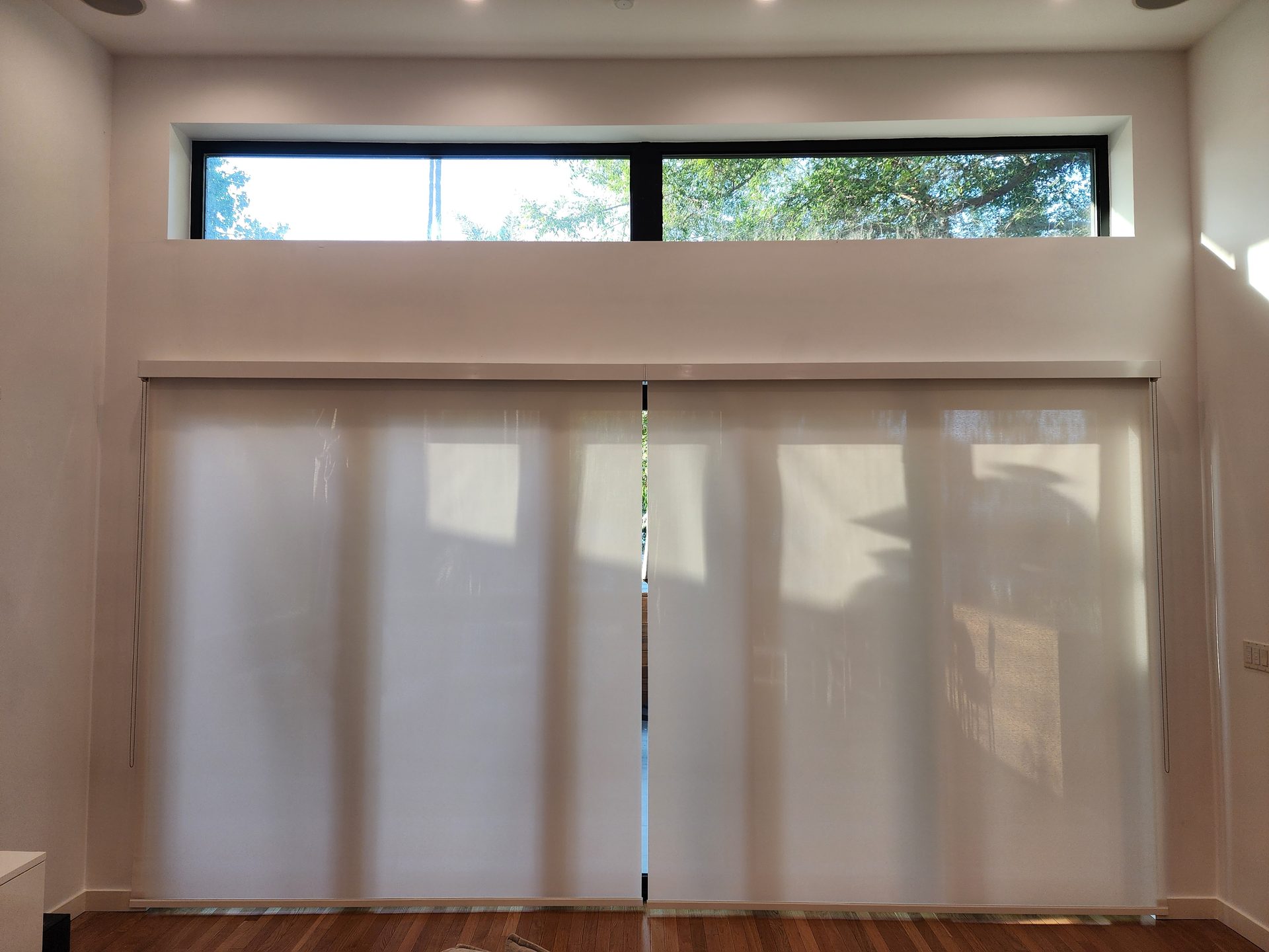 Motorized solar shades lowered across a wide multi-panel slider in a San Diego home
