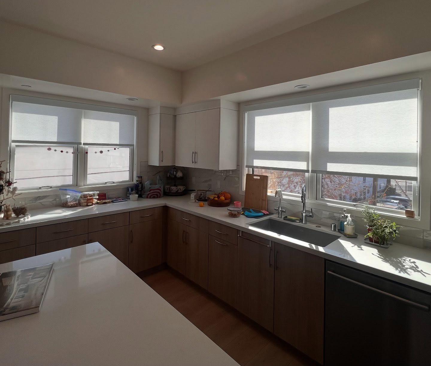 Roller shades across corner kitchen windows in a San Diego home