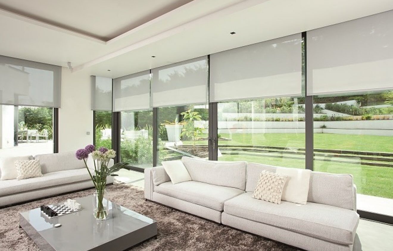 Solar shades lowered across a wall of glass in a San Diego living room, view to the garden still visible