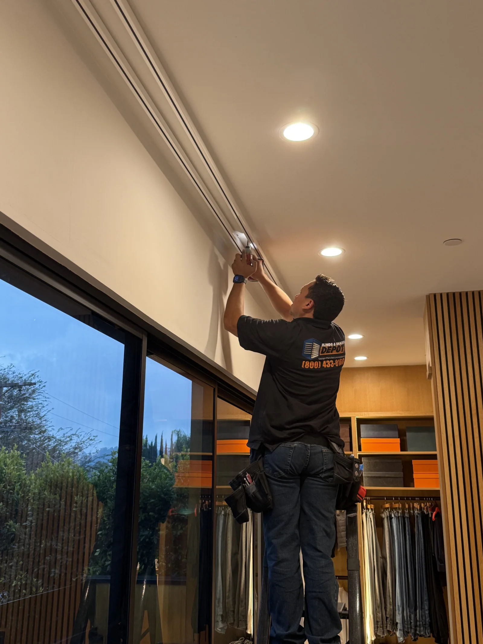 An installer fitting a shade above a wide window