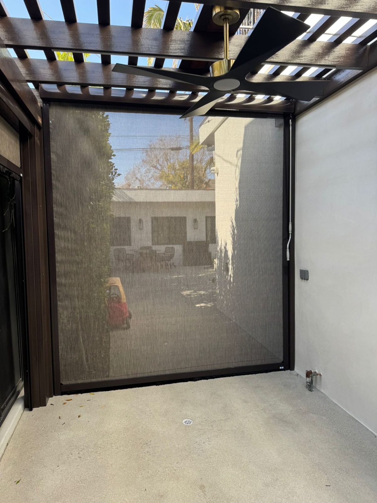 A zip screen fully down with the yard, trees and neighbouring house still visible through the mesh